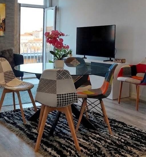 Living room with TV, tidy cabinet, green plant and yellow Clérigos Tower painting, Porto Skyline Residence